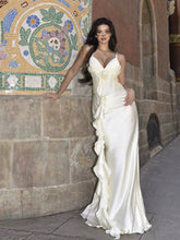 Woman in a white dress standing in front of a decorative mosaic wall.
